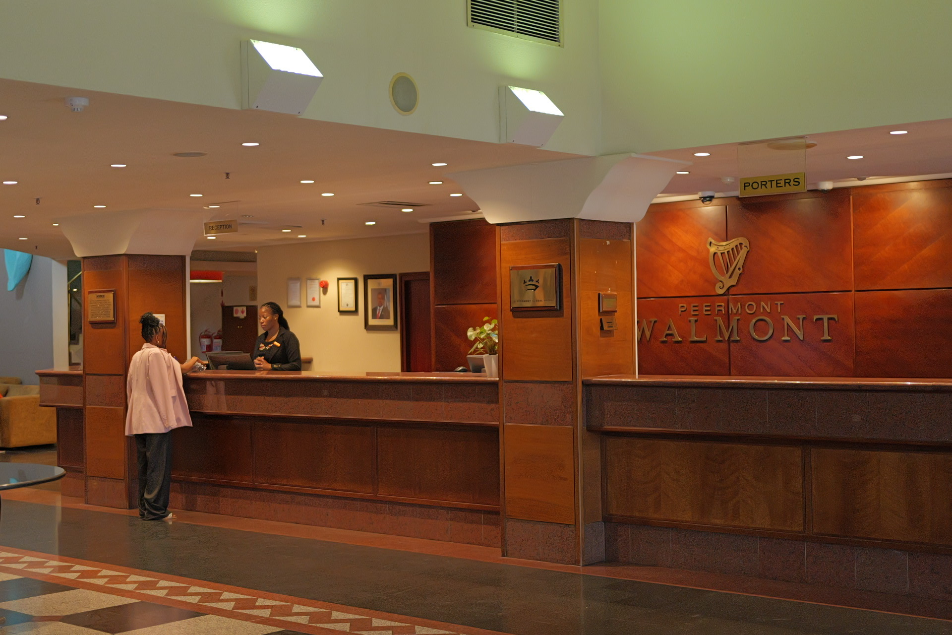 A receptionist assists a guest at the wooden Peermont Walmont front desk at The Grand Palm, Gaborone