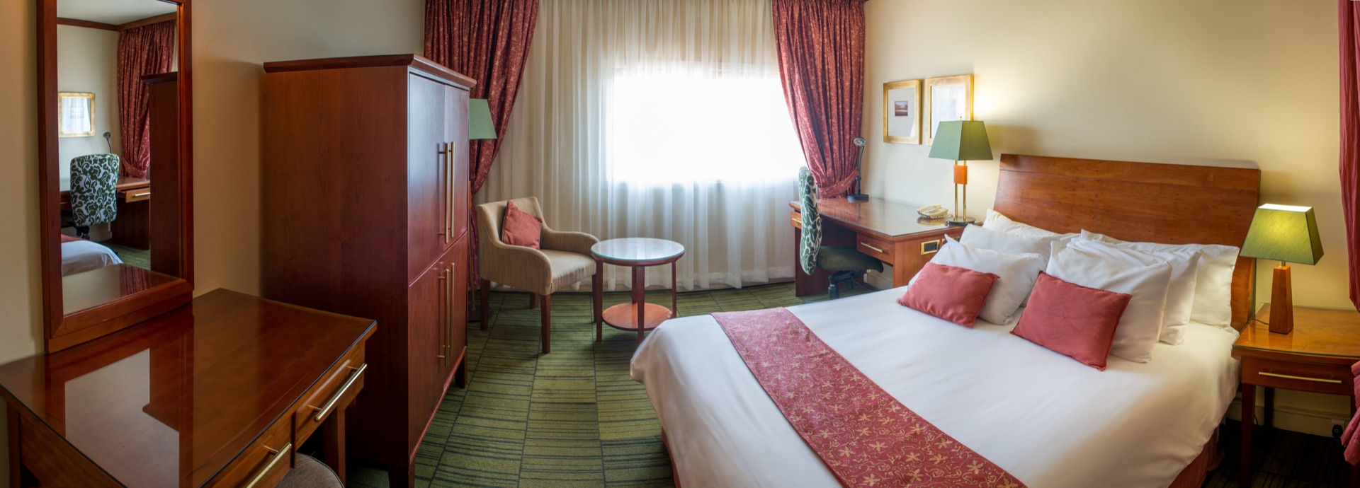Classic King room with king bed, armchair and writing desk at the Walmont, The Grand Palm, Gaborone