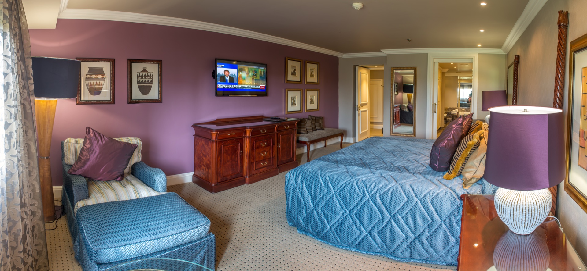 Junior Suite with king bed, blue armchair and purple feature wall at the Walmont, The Grand Palm, Gaborone