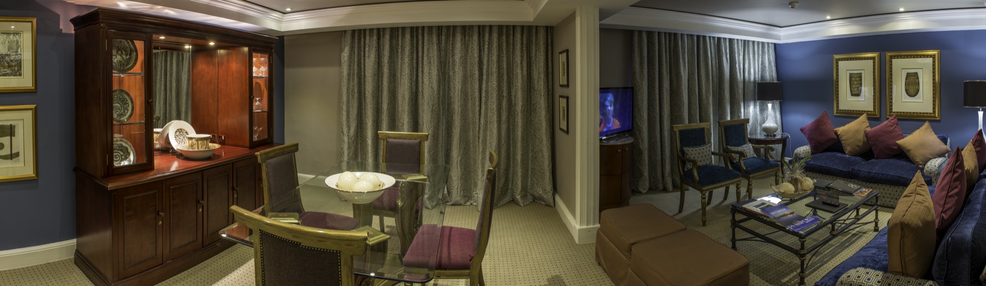 Presidential Suite lounge with dining table, cabinet and blue sofas at the Walmont, The Grand Palm, Gaborone