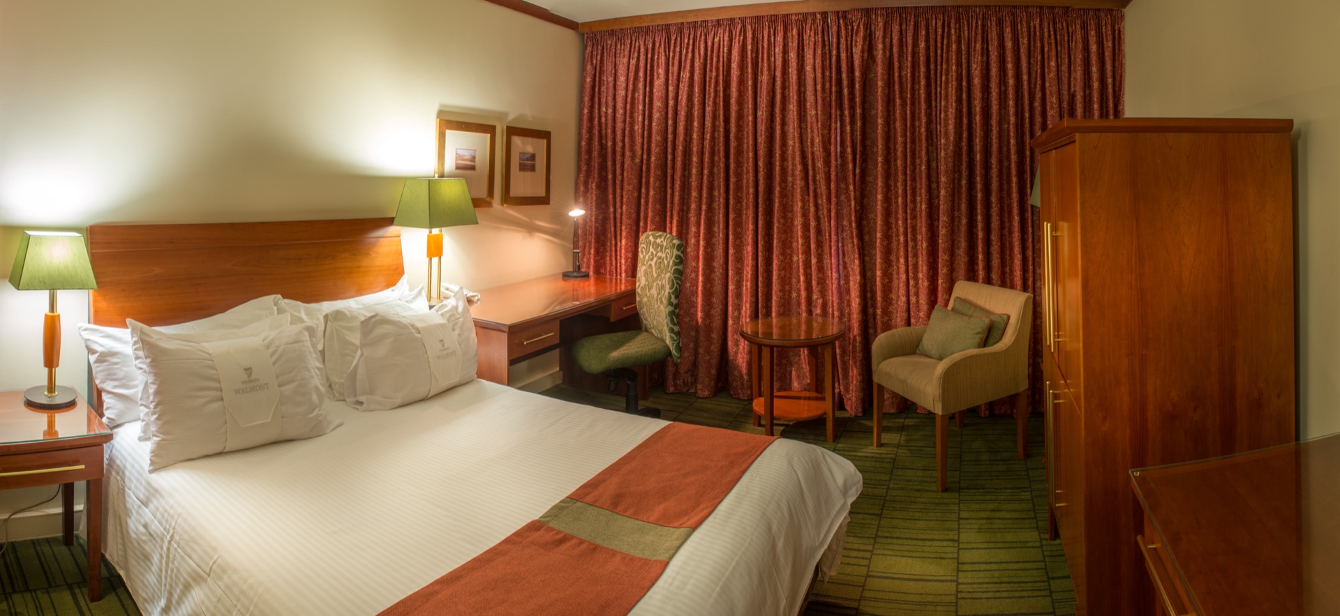 Superior King room with bed, desk and red draped window at the Walmont, The Grand Palm, Gaborone